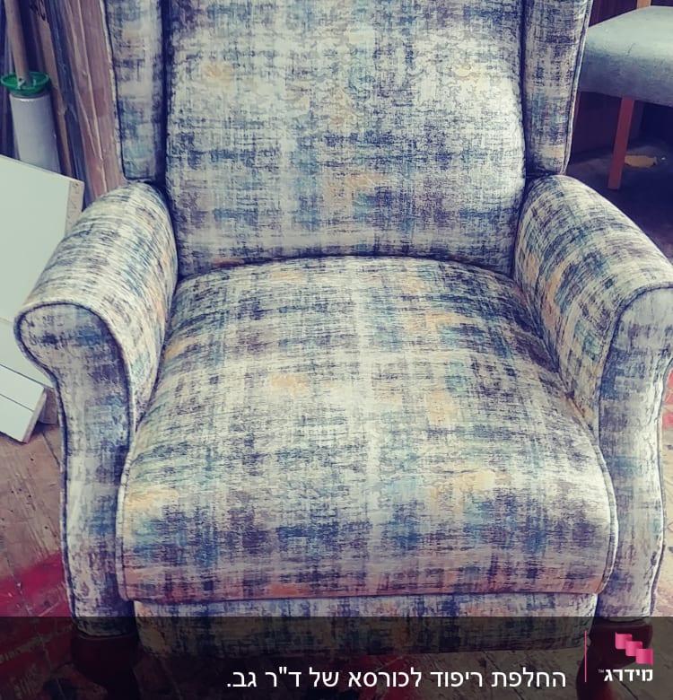 כורסה מרופדת בבד צבעוני על רצפת עץ